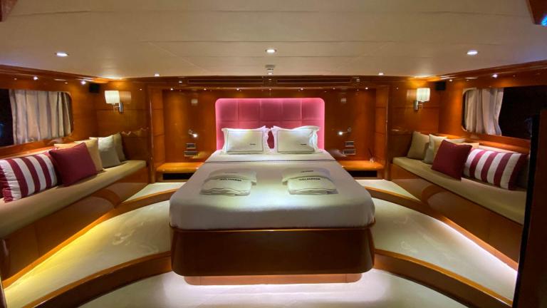 Das Schlafzimmer der Gulet ist geräumig und hat ein Bett mit einem rosa Kopfteil und Sofas mit Kissen